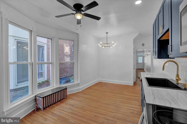 kitchen featuring a sink, tasteful backsplash, light wood-style floors, radiator heating unit, and baseboards