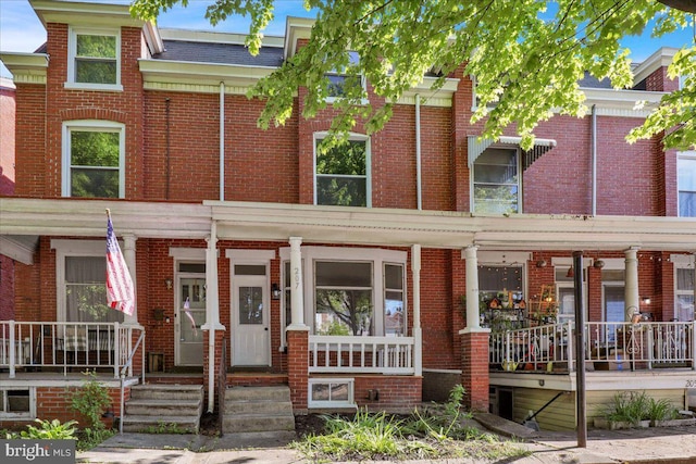 townhome / multi-family property with covered porch and brick siding