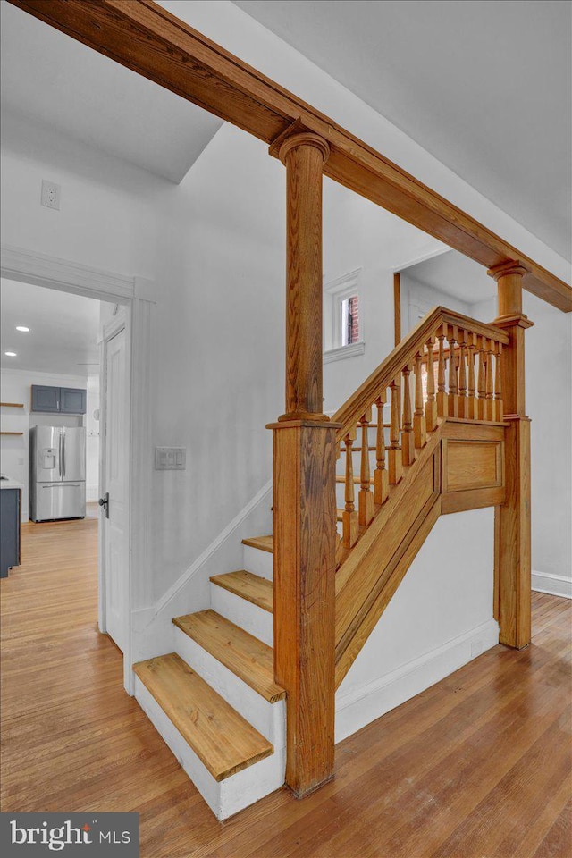 staircase featuring wood finished floors, baseboards, and recessed lighting