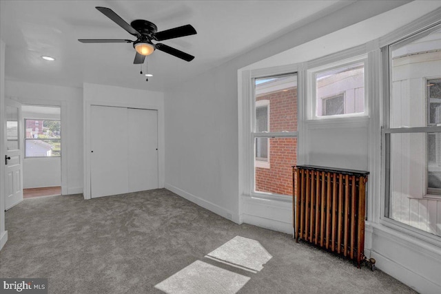 interior space with radiator heating unit, carpet flooring, ceiling fan, and baseboards