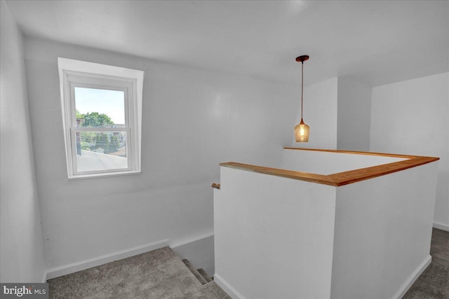 corridor with an upstairs landing, carpet floors, and baseboards