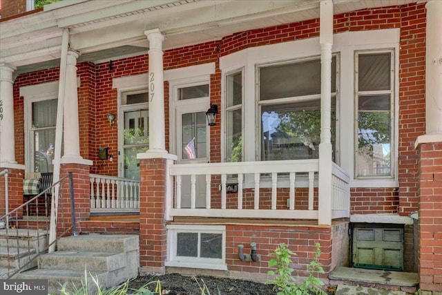 view of exterior entry featuring covered porch and brick siding
