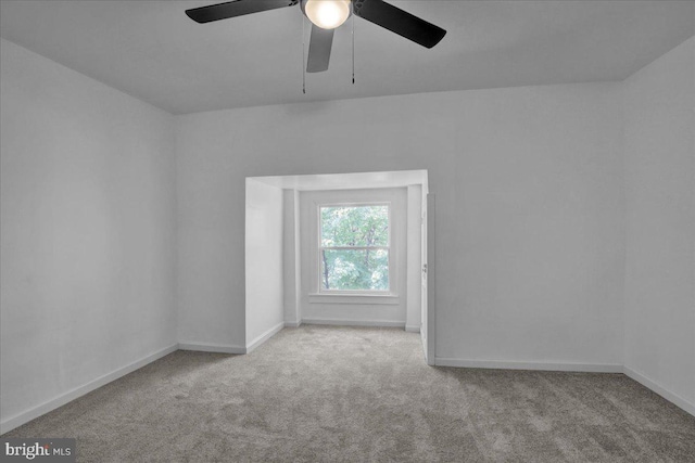 carpeted empty room featuring a ceiling fan and baseboards