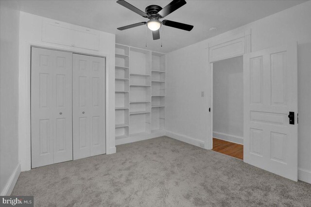 unfurnished bedroom featuring carpet flooring, a closet, baseboards, and a ceiling fan
