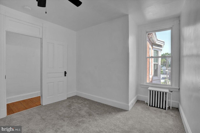 unfurnished bedroom with radiator heating unit, carpet flooring, baseboards, and ceiling fan