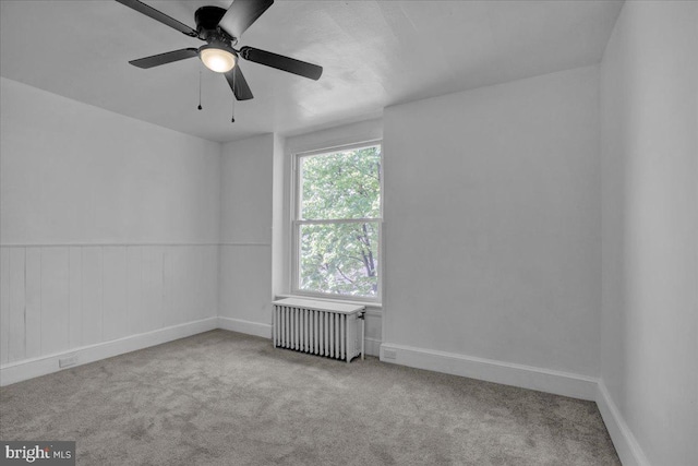 carpeted empty room featuring radiator heating unit, ceiling fan, and baseboards