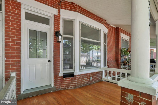 doorway to property with a porch and brick siding