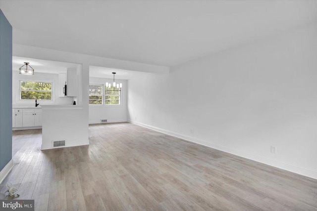 200 Boxwood Ln, Cinnaminson, NJ 08077 - unfurnished living room featuring a chandelier, light wood-style flooring, baseboards, and a sink