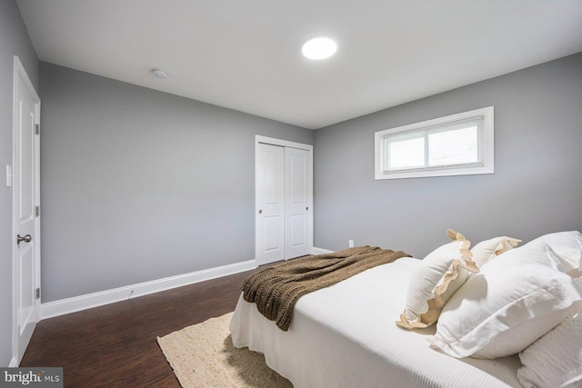 bedroom with dark wood-style floors, baseboards, and a closet