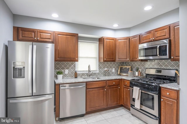 kitchen with appliances with stainless steel finishes, a sink, light stone countertops, tasteful backsplash, and recessed lighting