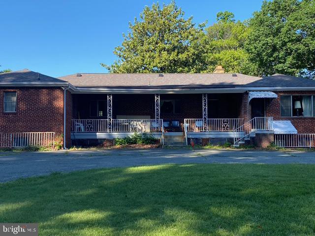 ranch-style house with brick siding, covered porch, and a front lawn