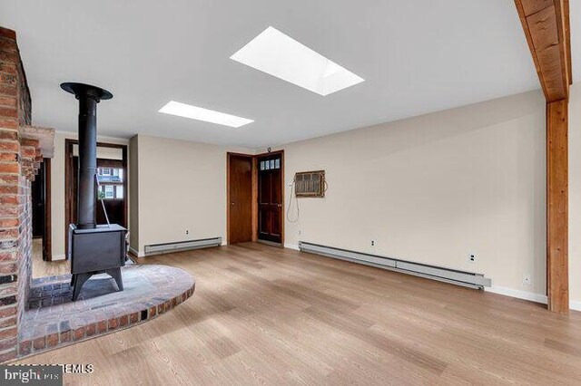 305 Nautilus Blvd, Forked River, NJ 08731 - unfurnished living room featuring a wood stove, baseboard heating, wood finished floors, and baseboards