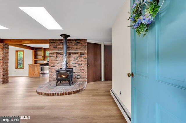 305 Nautilus Blvd, Forked River, NJ 08731 - living area featuring a baseboard heating unit, a skylight, wood finished floors, a wood stove, and baseboards