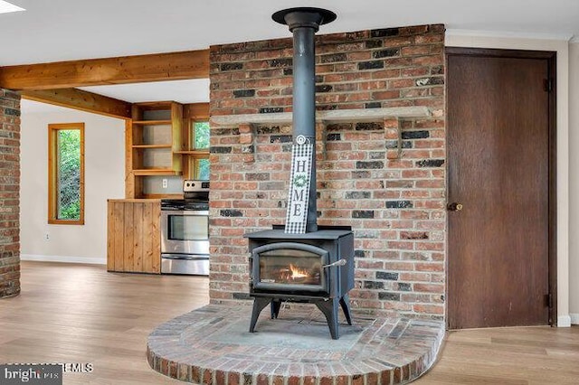 305 Nautilus Blvd, Forked River, NJ 08731 - detailed view of stainless steel electric range oven, a wood stove, baseboards, wood finished floors, and beamed ceiling