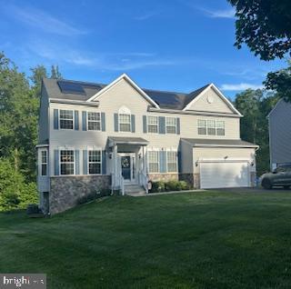 7571 Kindler Overlook Dr, Laurel, MD 20723 - view of front of property featuring a front yard, roof mounted solar panels, an attached garage, and stone siding