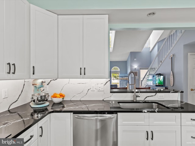 kitchen featuring stainless steel dishwasher, white cabinetry, and a sink