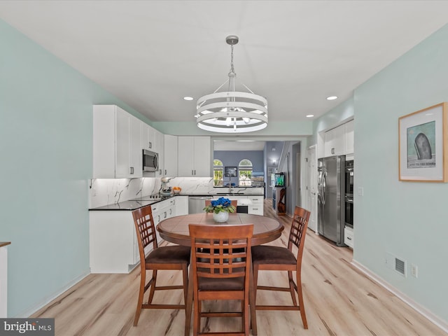 dining area with light wood-style floors, a chandelier, baseboards, and recessed lighting