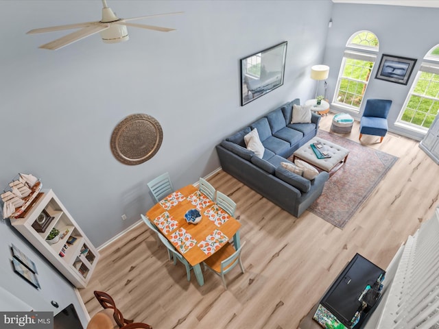 living room featuring wood finished floors, a ceiling fan, and baseboards