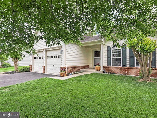view of property hidden behind natural elements featuring brick siding, driveway, a front lawn, and a garage