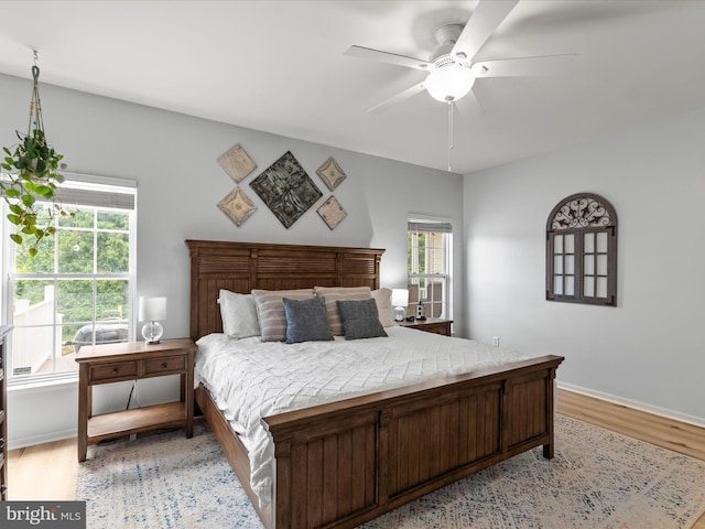 bedroom featuring light wood-style flooring, multiple windows, ceiling fan, and baseboards
