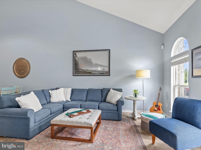 living area with high vaulted ceiling, wood finished floors, and baseboards