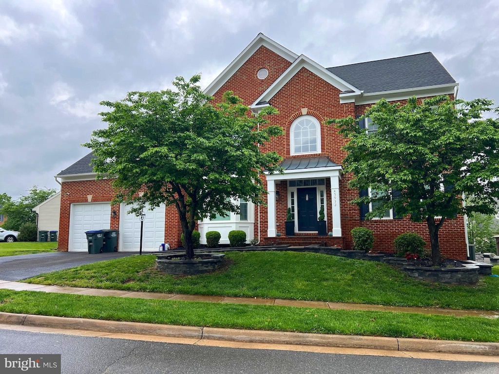 view of front of home featuring brick siding, driveway, and a front yard