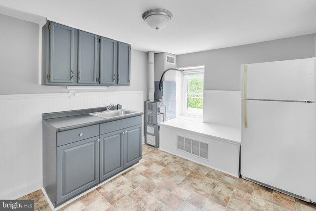 700 Strahle St, Philadelphia, PA 19111 - kitchen with freestanding refrigerator, a sink, a wainscoted wall, and stone finish floors