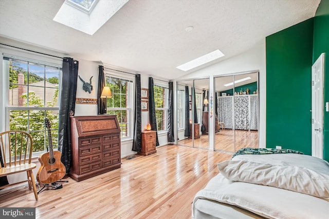 1559 Autumn Ridge Cir, Reston, VA 20194 - bedroom featuring a skylight, light wood-style flooring, vaulted ceiling, multiple closets, and a textured ceiling