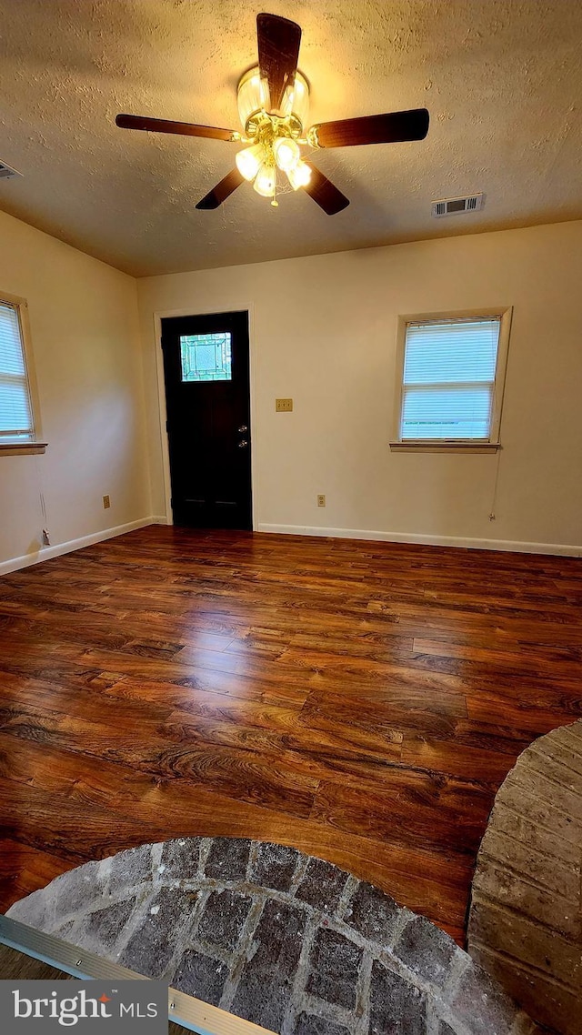 foyer with a textured ceiling, wood finished floors, a ceiling fan, and baseboards