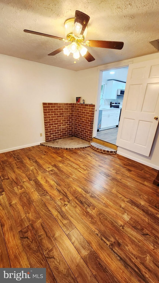 unfurnished room featuring a textured ceiling, wood finished floors, a ceiling fan, and baseboards