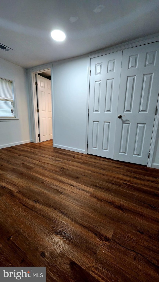 empty room with dark wood-style floors and baseboards