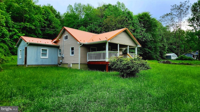 back of house with metal roof, an outbuilding, covered porch, and a storage unit