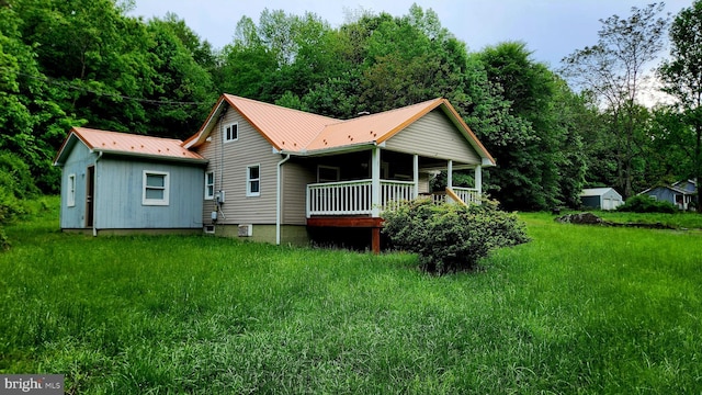 back of property with metal roof, covered porch, an outdoor structure, and a shed