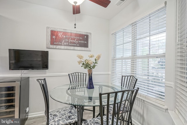 dining area featuring wine cooler, a ceiling fan, and wood finished floors