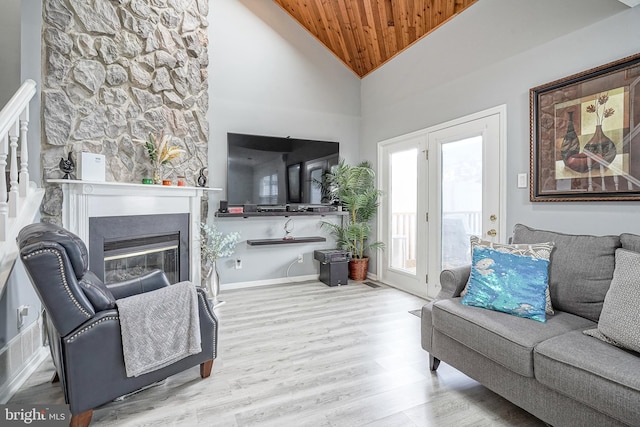 living area featuring wood ceiling, wood finished floors, a glass covered fireplace, and high vaulted ceiling