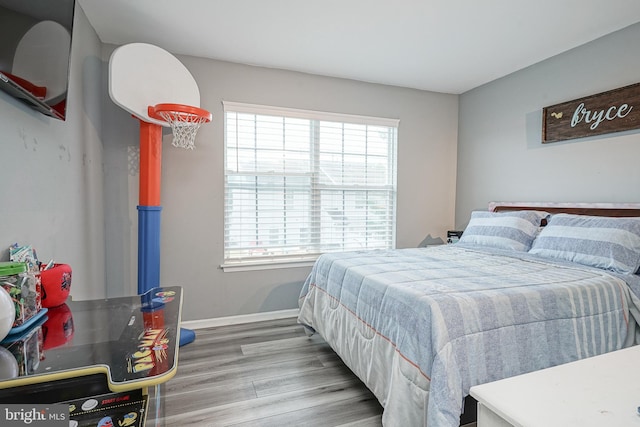 bedroom with wood finished floors, multiple windows, and baseboards