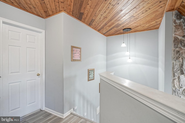corridor featuring wooden ceiling, an upstairs landing, wood finished floors, ornamental molding, and baseboards
