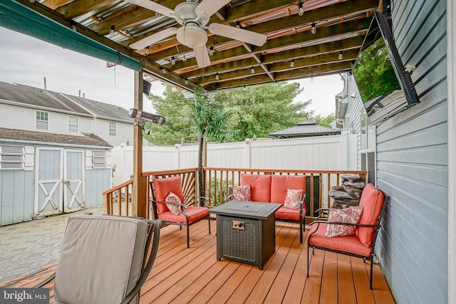 wooden deck with outdoor lounge area, a storage shed, a fenced backyard, an outbuilding, and ceiling fan