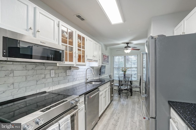 kitchen with stainless steel appliances, a sink, white cabinets, and tasteful backsplash