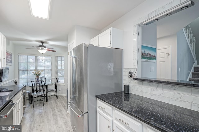 kitchen with stainless steel appliances, ceiling fan, white cabinetry, dark stone countertops, and light wood finished floors
