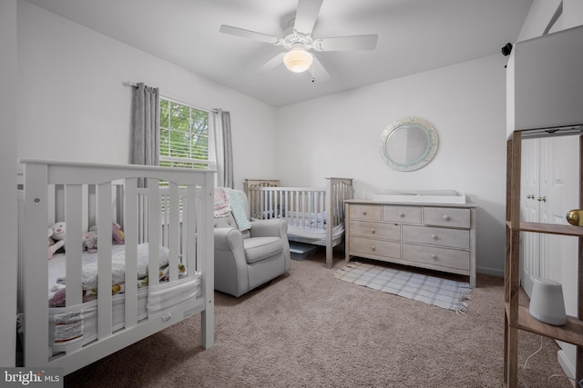 bedroom featuring carpet flooring, a crib, and ceiling fan