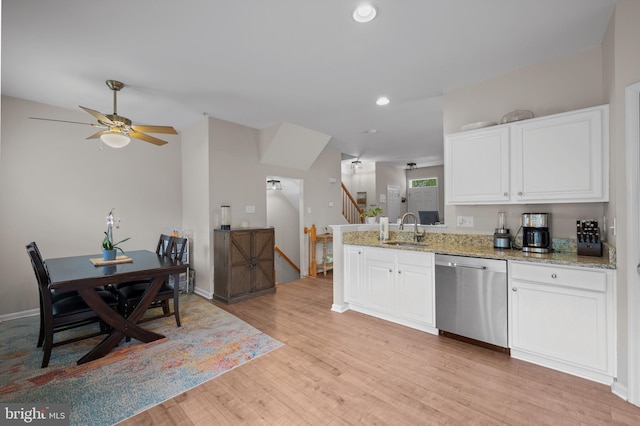 kitchen featuring stainless steel dishwasher, a sink, ceiling fan, light stone countertops, and light wood-style flooring