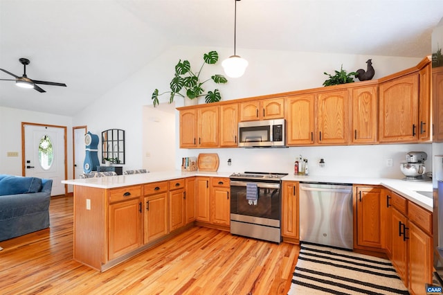 kitchen with appliances with stainless steel finishes, vaulted ceiling, a peninsula, open floor plan, and light countertops