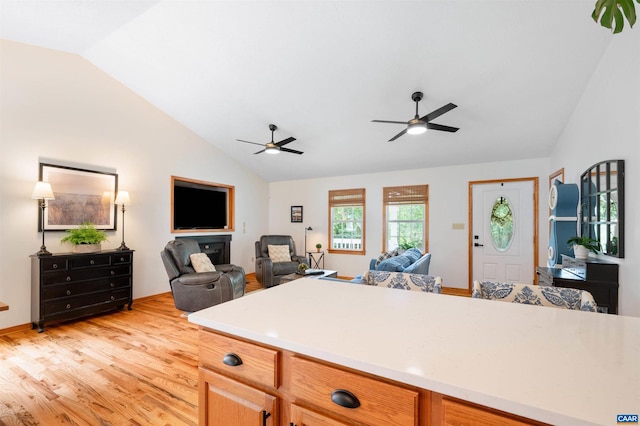 kitchen with open floor plan, lofted ceiling, a ceiling fan, light countertops, and light wood-type flooring