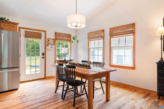 dining space featuring light wood-type flooring, baseboards, and lofted ceiling