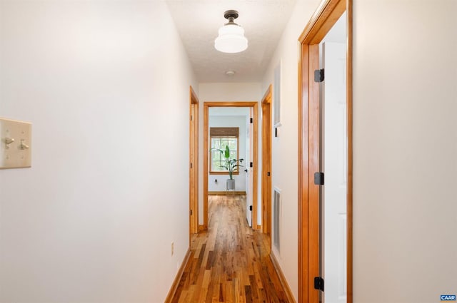 hallway with light wood-type flooring and baseboards