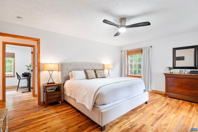 bedroom featuring light wood finished floors, baseboards, and a textured ceiling