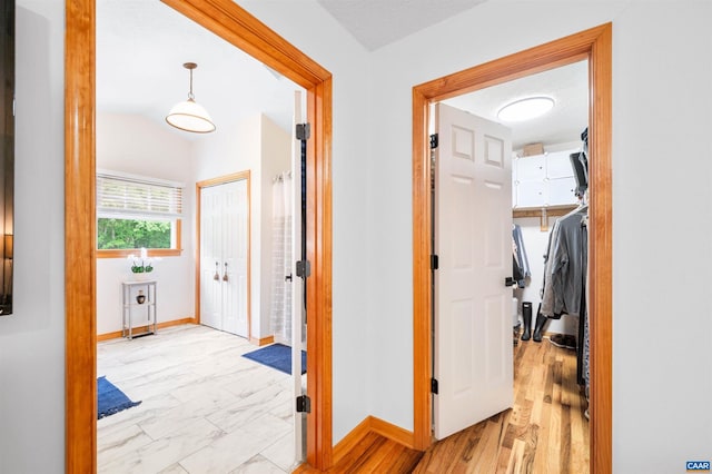 hall featuring baseboards and light marble finish flooring