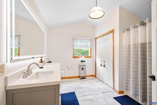 bathroom featuring marble finish flooring, vanity, toilet, baseboards, and vaulted ceiling