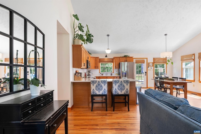 kitchen with appliances with stainless steel finishes, light wood-style floors, a peninsula, light countertops, and brown cabinets